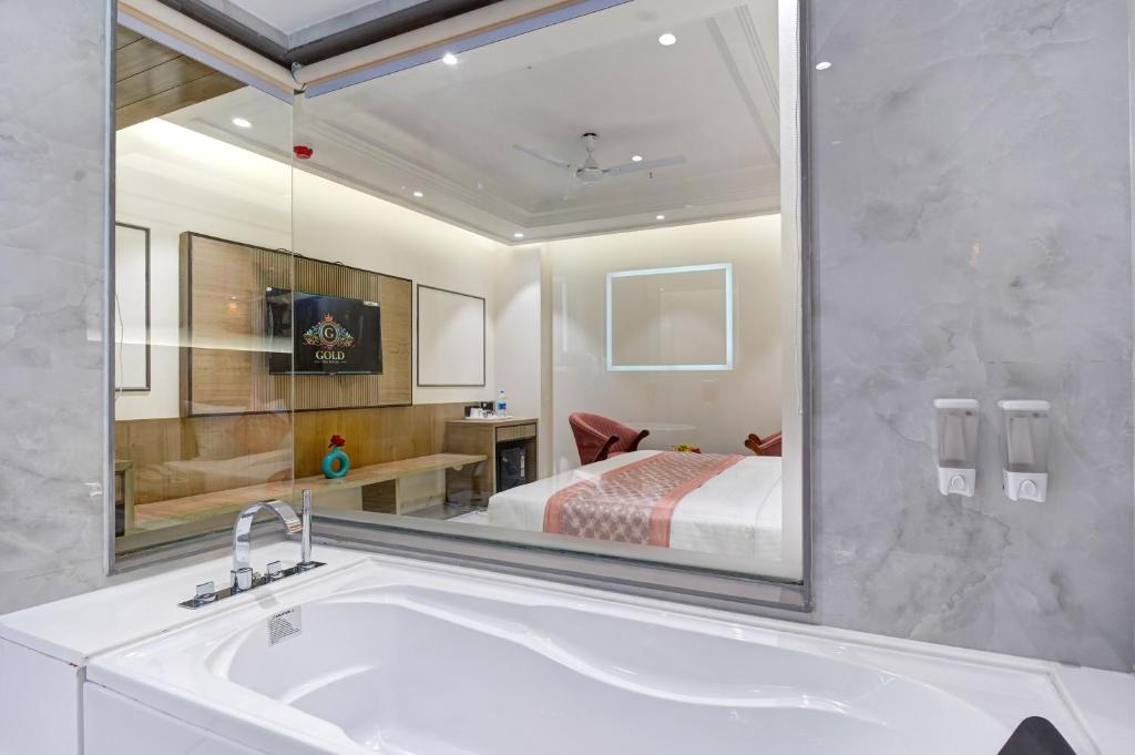 a bathroom with a sink and a bed in a mirror at Hotel Gold The Royal A Luxurious Stay- Near New Delhi Railway Station & Connaught Place in New Delhi