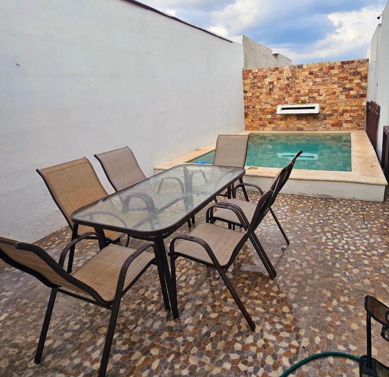 a patio with a glass table and chairs next to a swimming pool at Departamento con piscina GREEN in Mérida