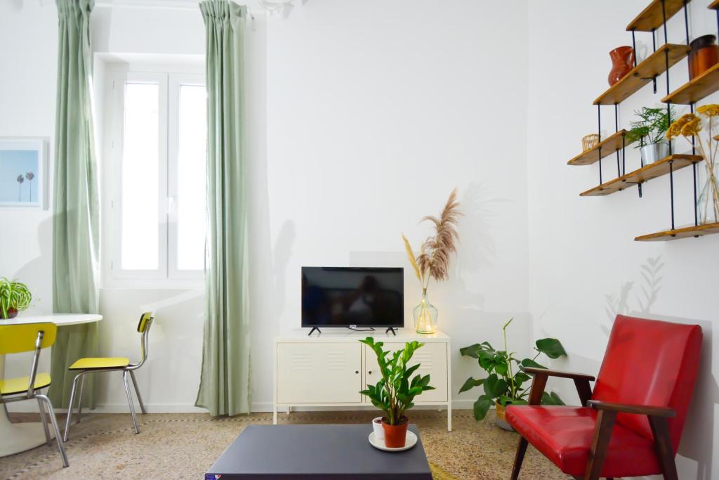 - un salon avec une télévision et une chaise rouge dans l'établissement Arceaux, à Montpellier