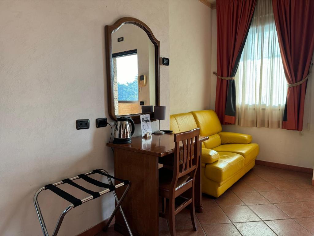 a room with a mirror and a desk and a yellow couch at EURO HOUSE INN airport in Fiumicino