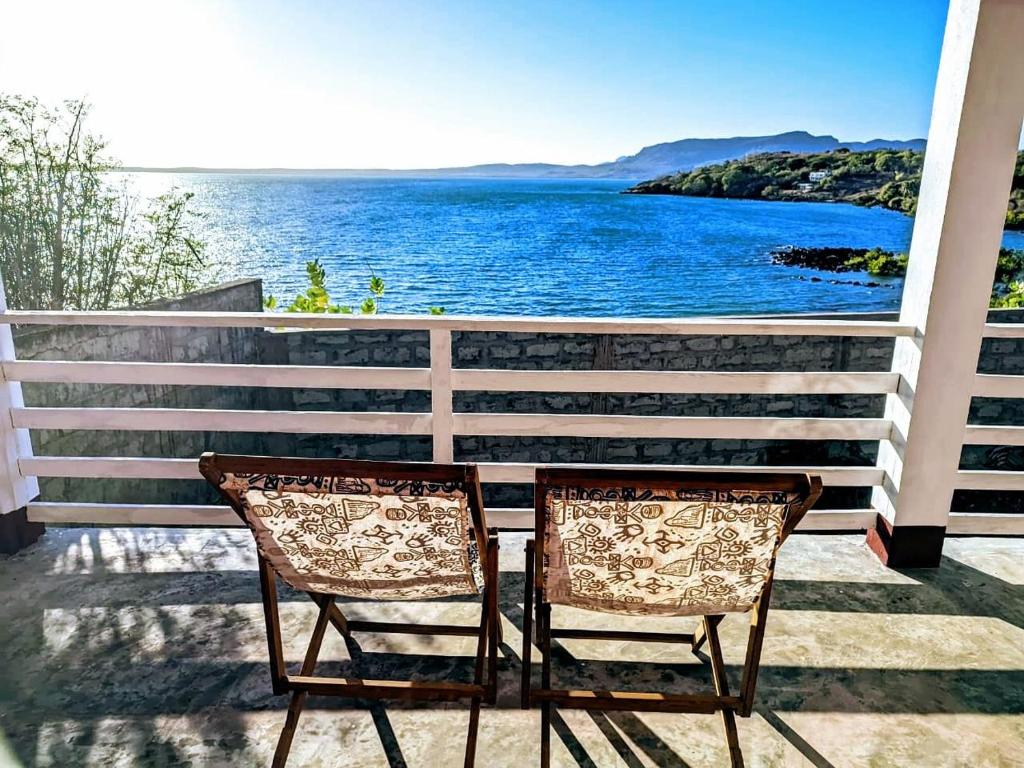 two chairs sitting on a porch overlooking the water at Maison en bord de mer in Diego Suarez