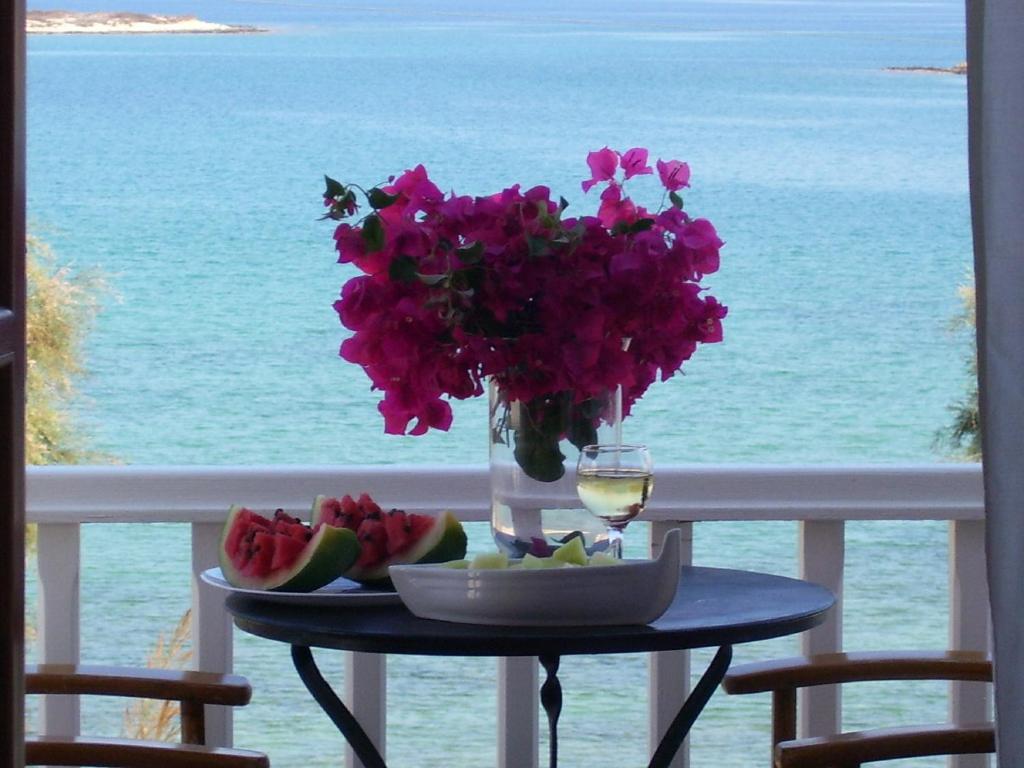 a table with a vase of flowers and a glass of wine at Roussos Beach Hotel in Naousa