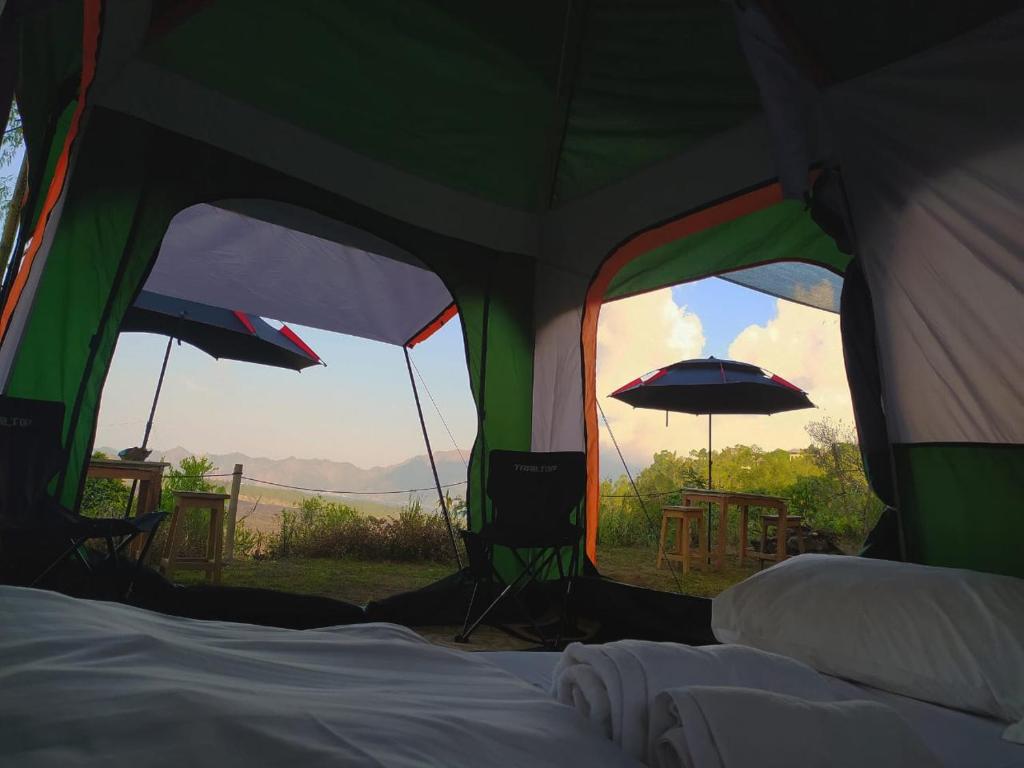 a tent with two windows and a table and an umbrella at Kintamani Adventures 'Hide in Nature lodge' in Kintamani