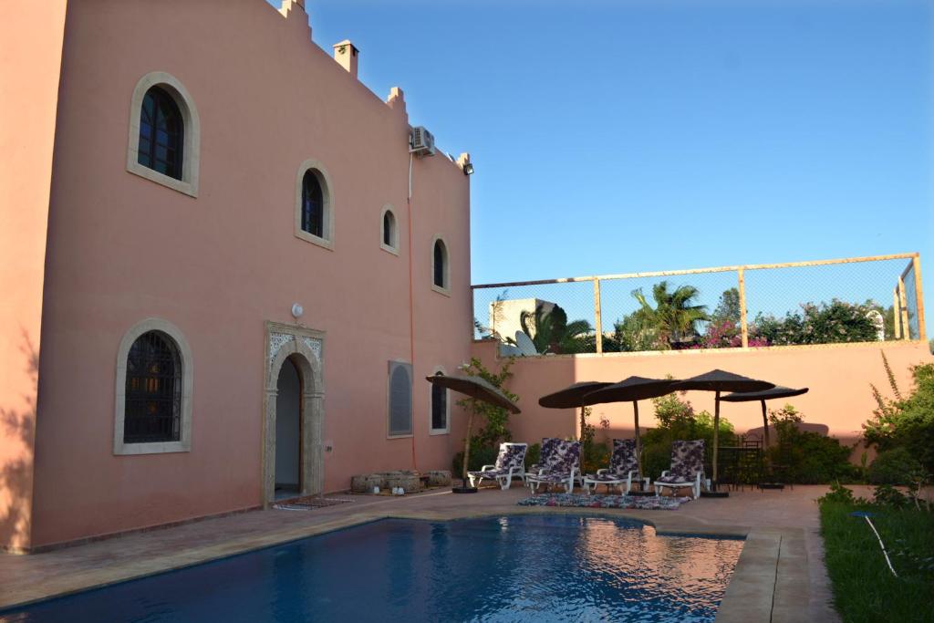 Una piscina con sillas y sombrillas al lado de un edificio. en Riad Aïcha Addi - Poolside - Traditional Moroccan, en Essaouira