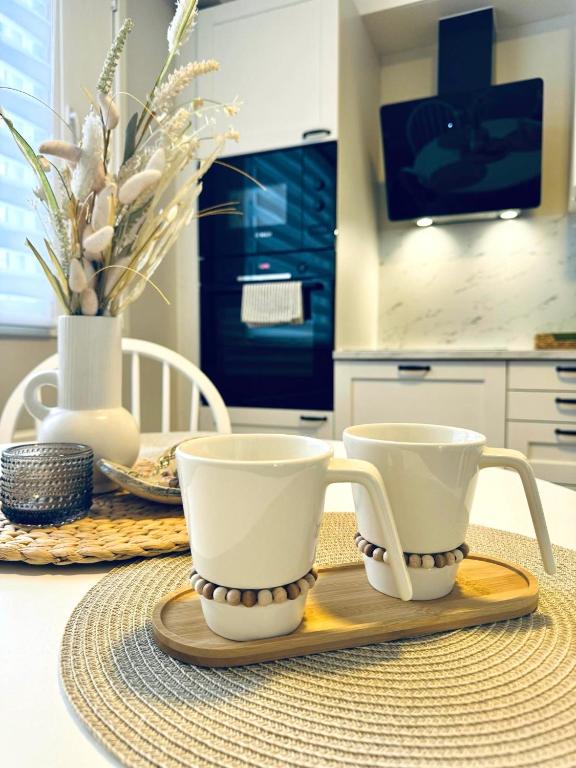 two coffee cups sitting on a wooden tray on a table at Apartment Tullikatu in Kristinestad