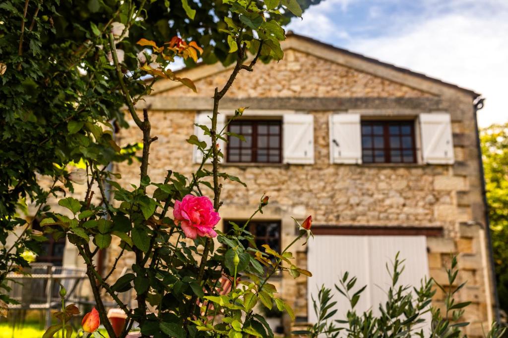 ein Backsteinhaus mit einer rosa Rose davor in der Unterkunft Maison au cœur de Saint-Émilion in Saint-Christophe-des-Bardes