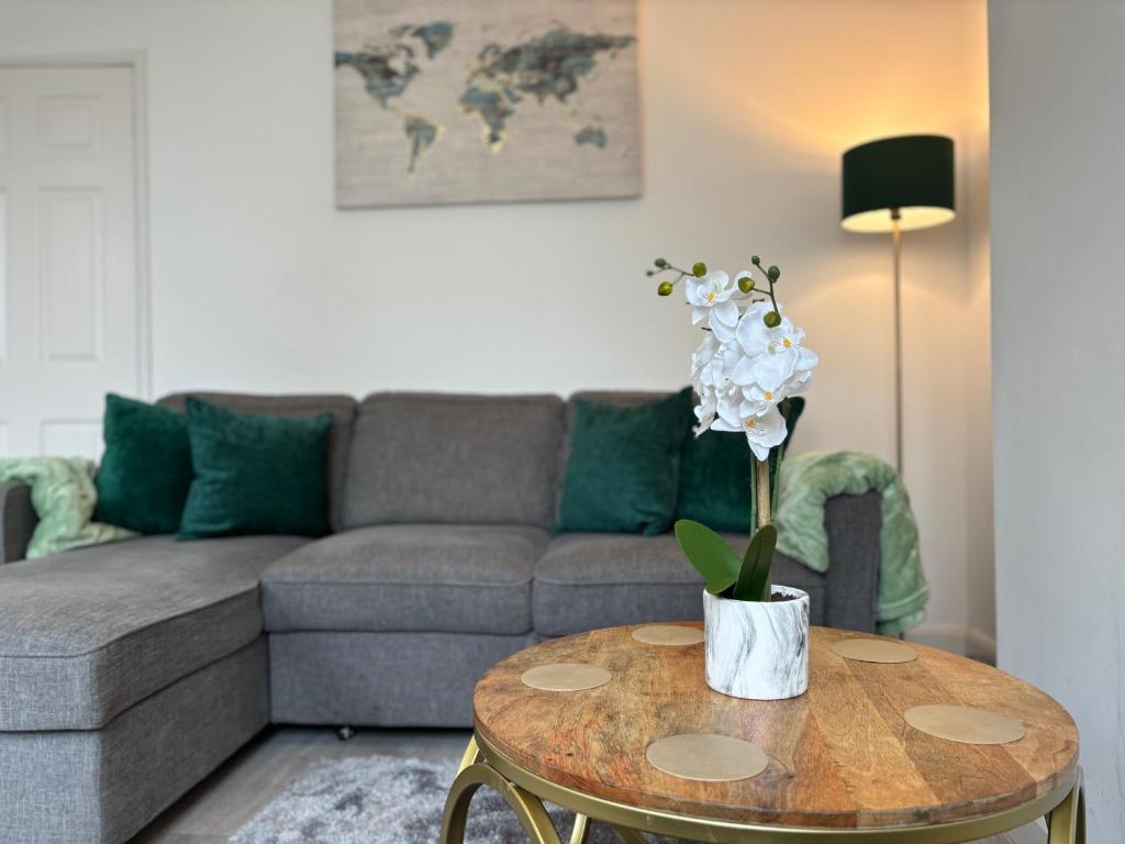 a living room with a couch and a table with flowers on it at Star Road Home, central location, FREE parking in Peterborough
