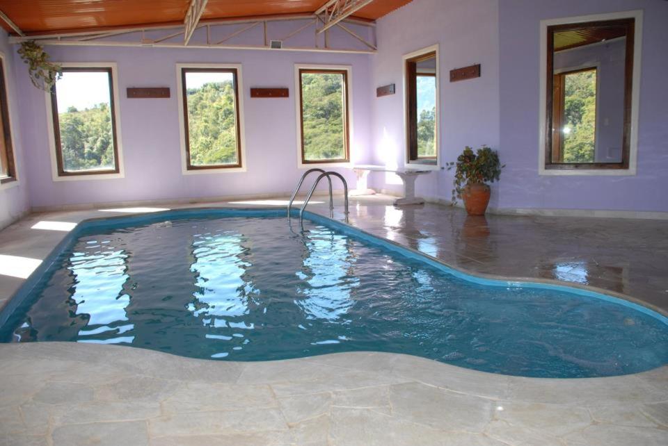 - une grande piscine dans une pièce dotée de fenêtres dans l'établissement Estrela da Serra Hotel Fazenda, à Santo Antônio do Pinhal