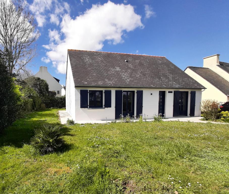 a white house with blue windows and a yard at Ty Bihan in Crozon