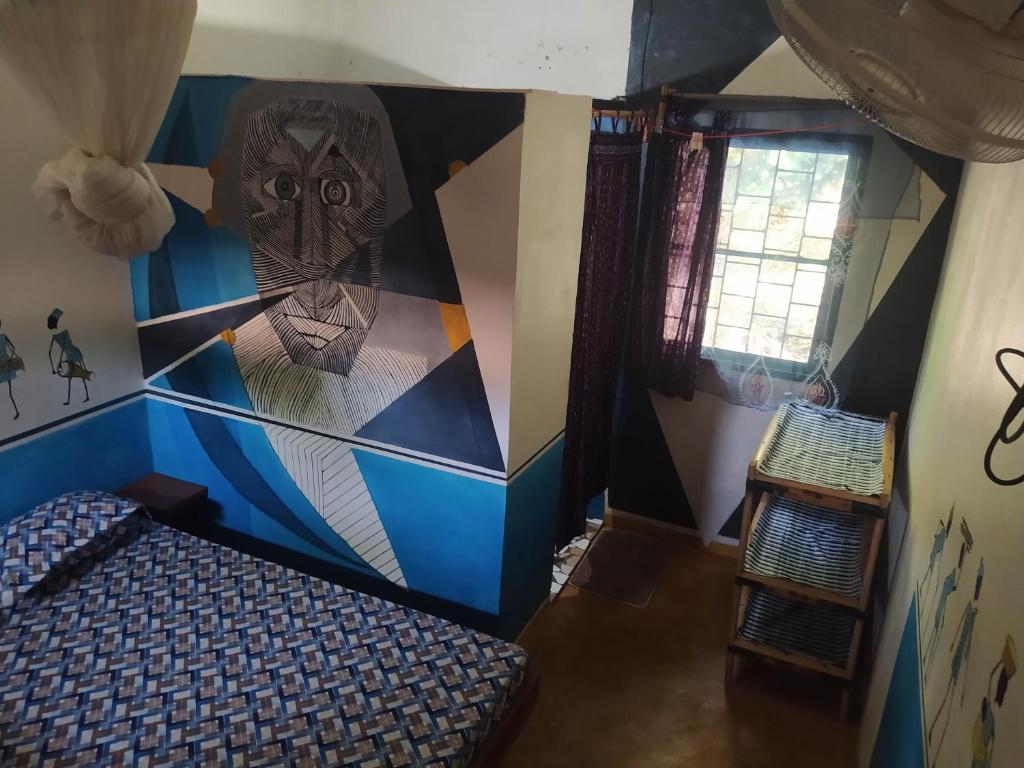 a room with a wall with a mural of an owl at Chez Yaya, chambre bleue in Oussouye