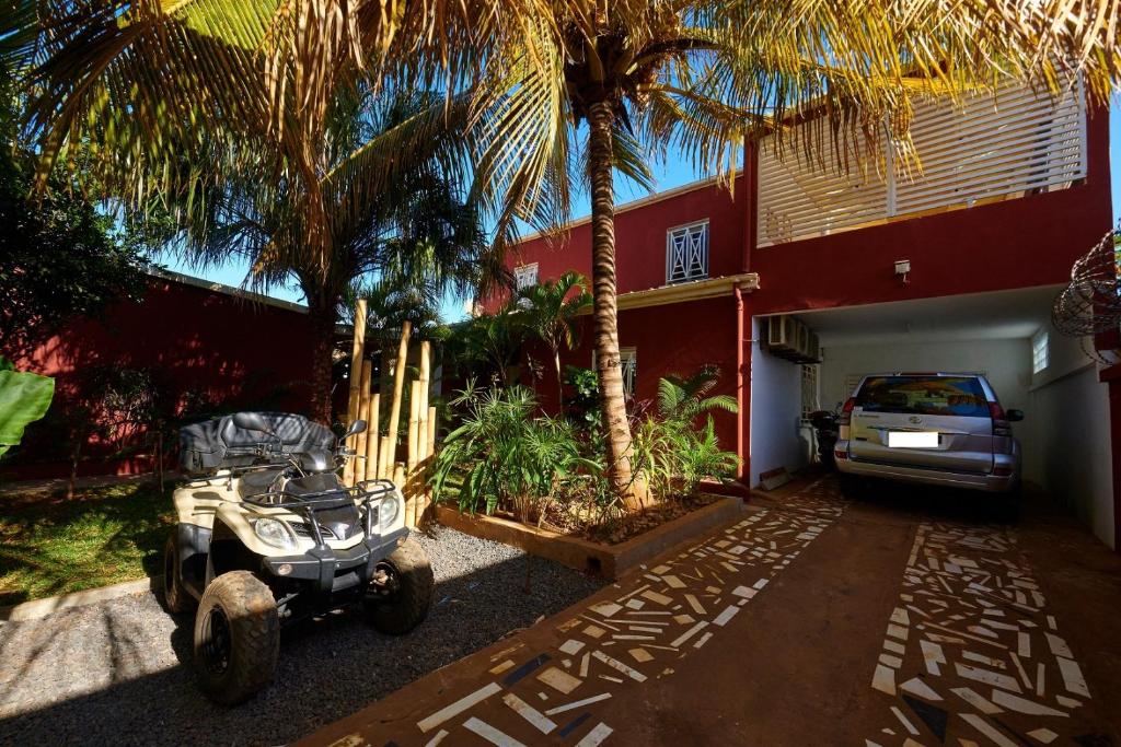 a quad bike parked in front of a house with palm trees at Chez Nounou in Diego Suarez