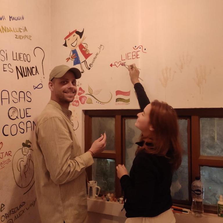 a man and a woman standing in a room writing on a wall at Milestone Homestay Agra in Tājganj