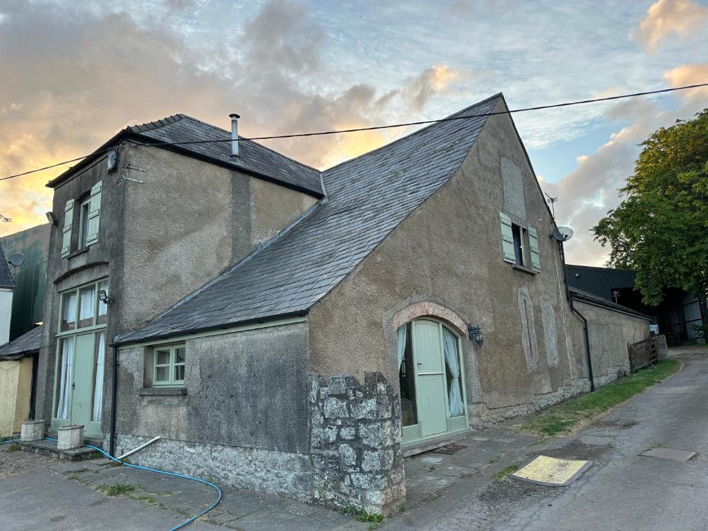 una antigua casa de piedra con techo negro en The Old Dairy, en Chepstow