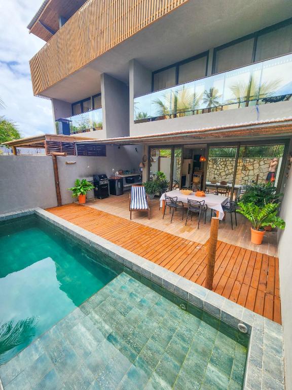 a house with a swimming pool in front of a house at Kanui Casa Maré 107 in São Miguel dos Milagres