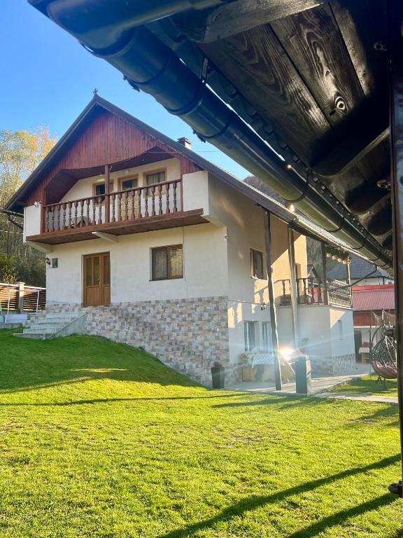 a house with a grass yard in front of it at Cabana Baraj Apuseni Mountains in Mihoeşti