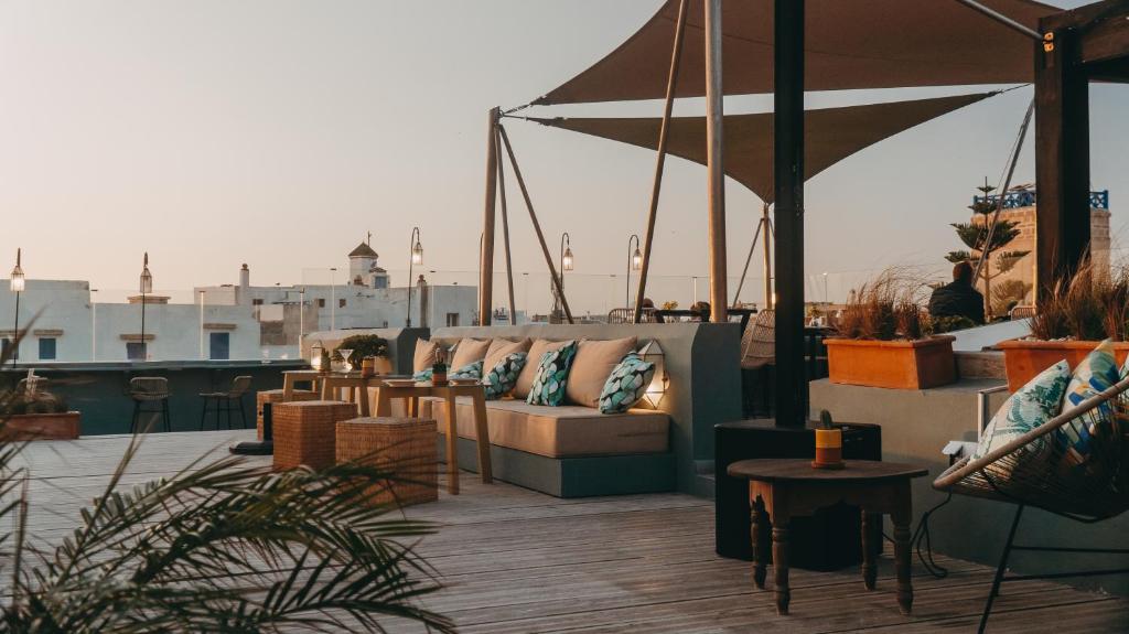 a rooftop patio with couches and tables and an umbrella at Le Palazzo in Essaouira