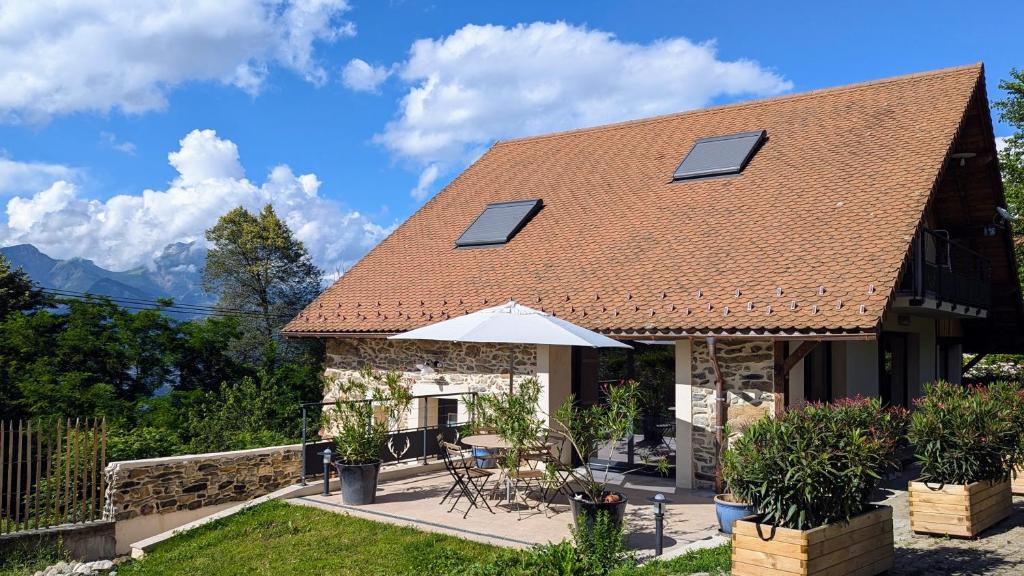une maison avec un toit, une table et un parasol dans l'établissement Gîte de Charme de Combeloup, à Murianette
