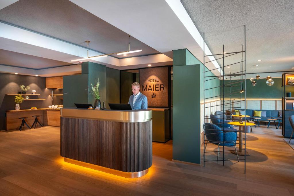 Un hombre de pie en un bar en el vestíbulo de un hotel. en Hotel Maier, en Friedrichshafen