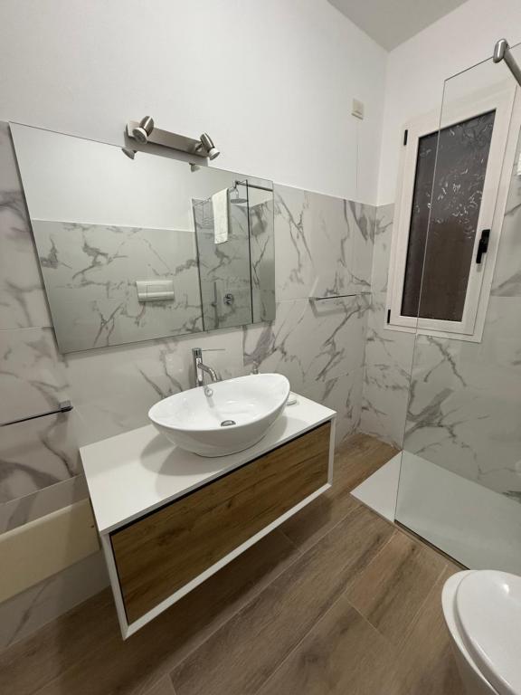 Un baño blanco con lavabo y espejo. en Marco’s Home, en Olbia