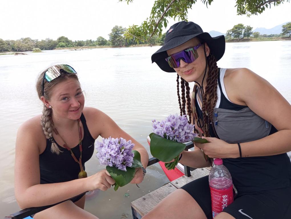two women sitting on a boat with flowers at SIGIRI HUNTER HOMESTAY Hostel & Guide Room in Sigiriya