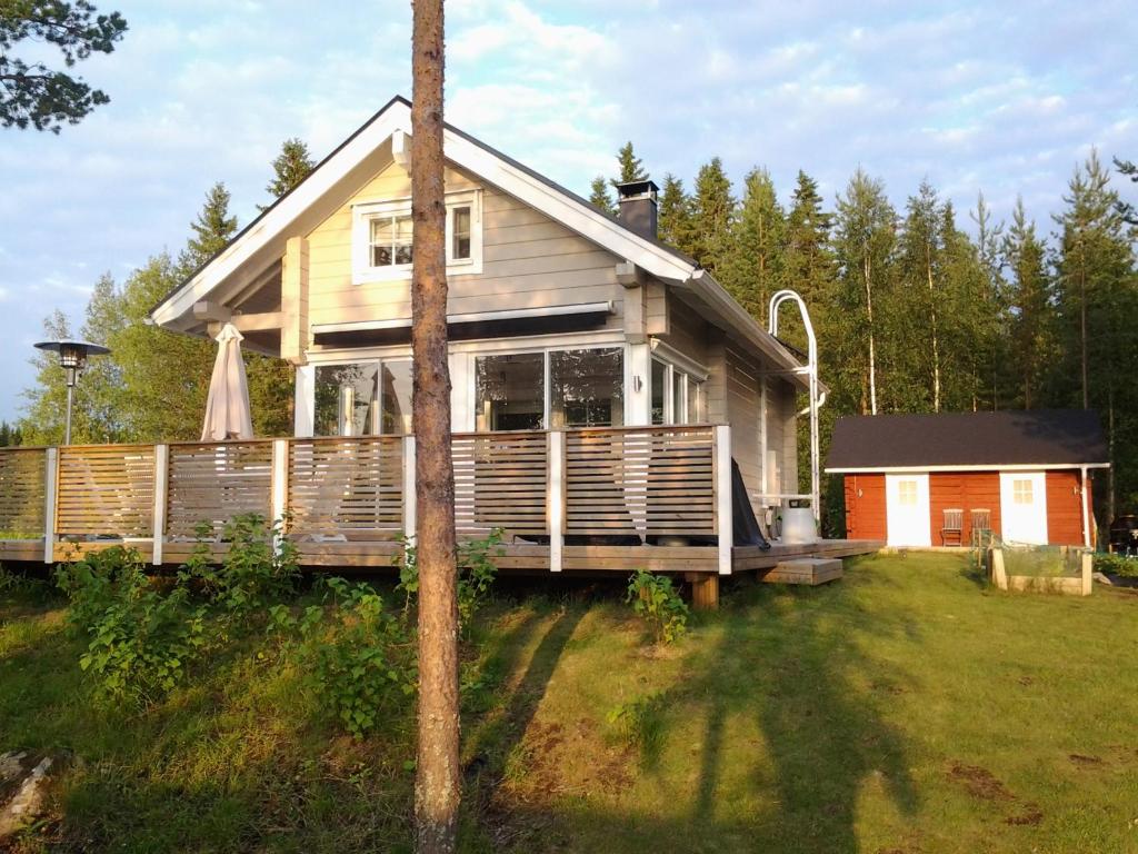 a large house with a large porch on a lawn at Sammalkalliontie 83 Lodge in Kinnula