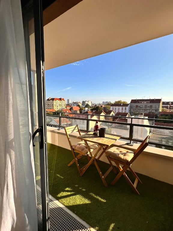 d'un balcon avec deux chaises et une table sur le toit. dans l'établissement Le Valmy, à Colombes