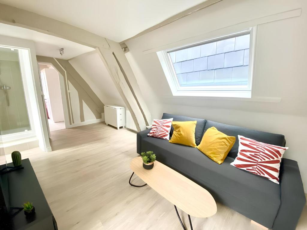 un salon avec un canapé bleu avec des coussins jaunes et rouges dans l'établissement Saint Romain 3, à Rouen