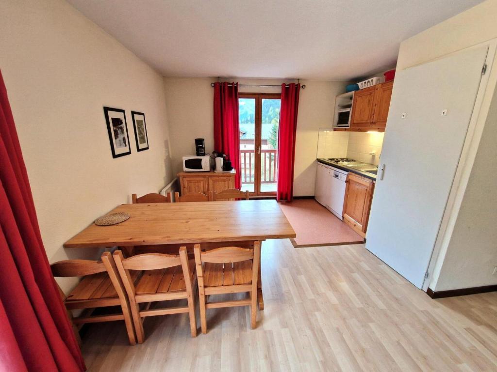 une cuisine et une salle à manger avec une table et un réfrigérateur dans l'établissement Les Chalets D'arrondaz - Appartement 3 pièces 4/6 personnes 36 m² MAE-2921, à Modane