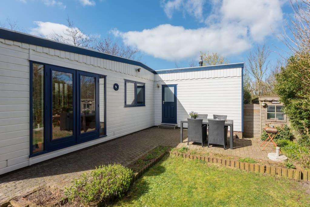 a white house with blue doors and a yard at Het Zeepaardje Petten aan Zee in Petten