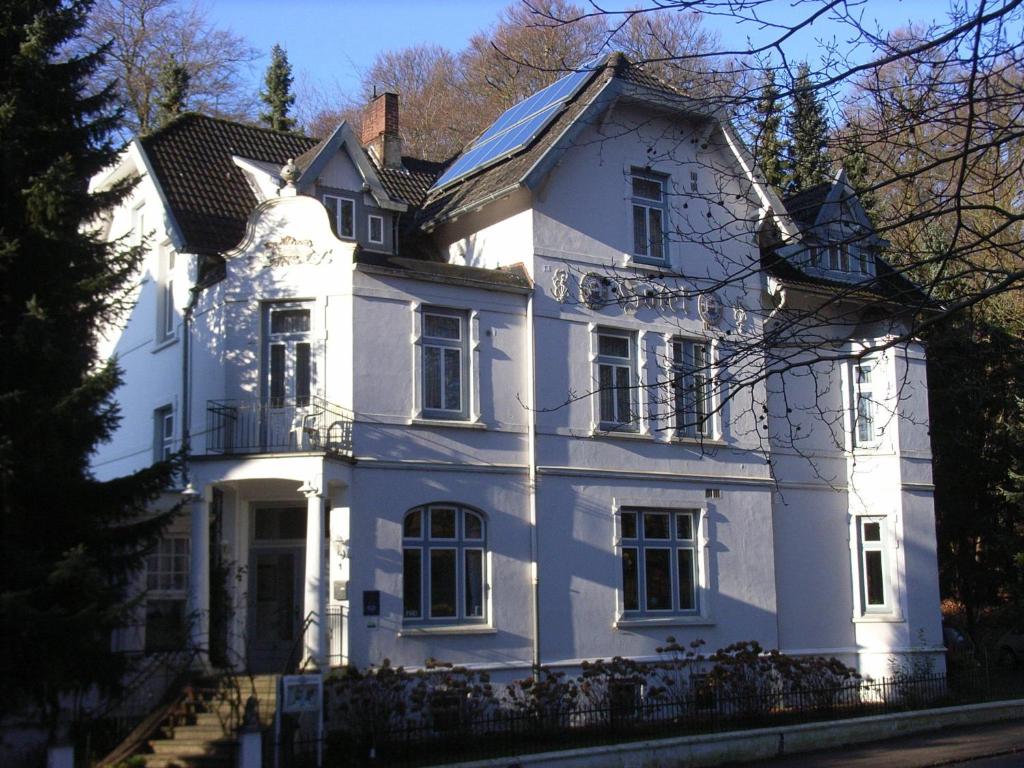 a large white house with a roof at Hotel Villa im Steinbusch in Malente