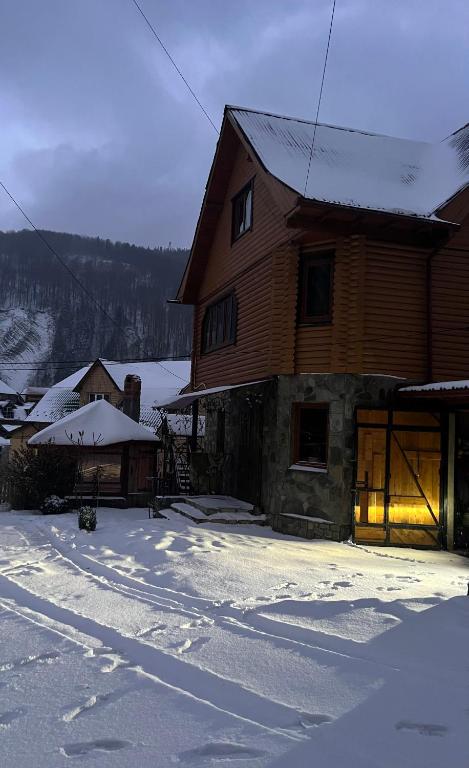 a large wooden house with snow on the ground at Cottage u Romana in Yaremche