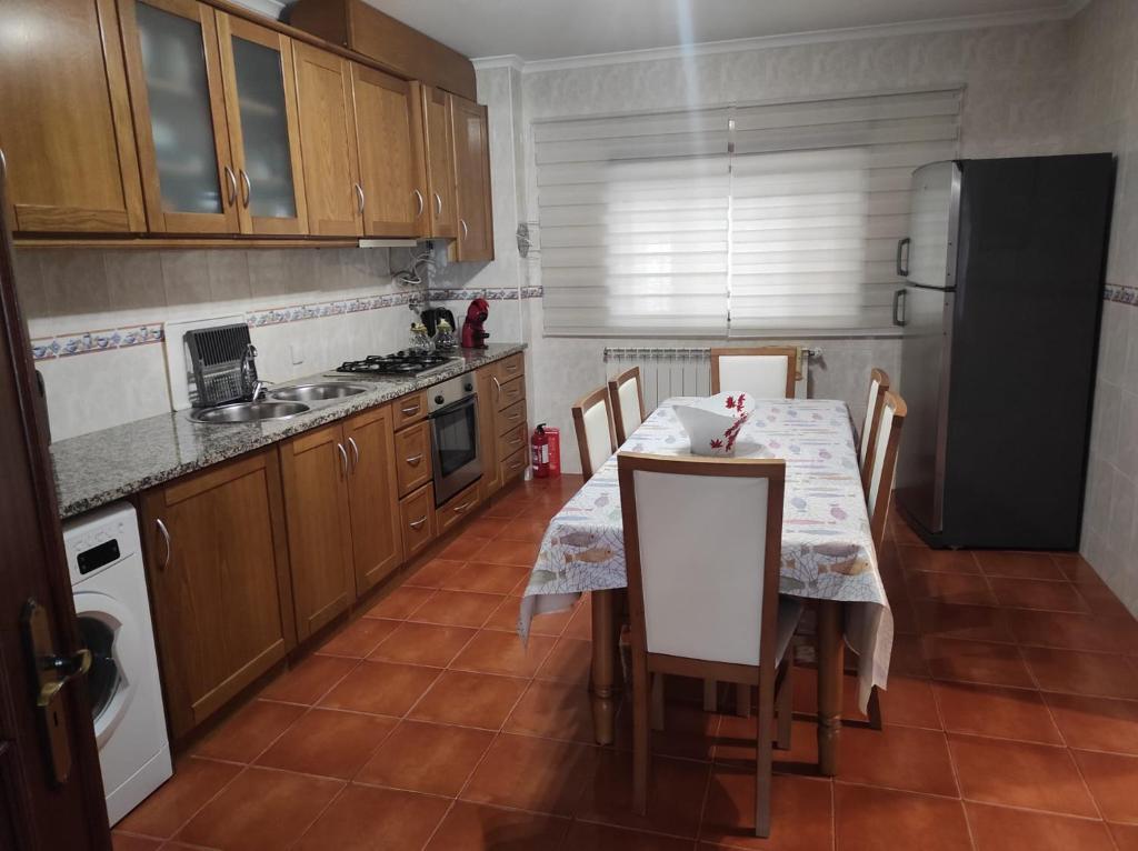 a kitchen with a table with chairs and a refrigerator at Casa Lúcia in Nazaré