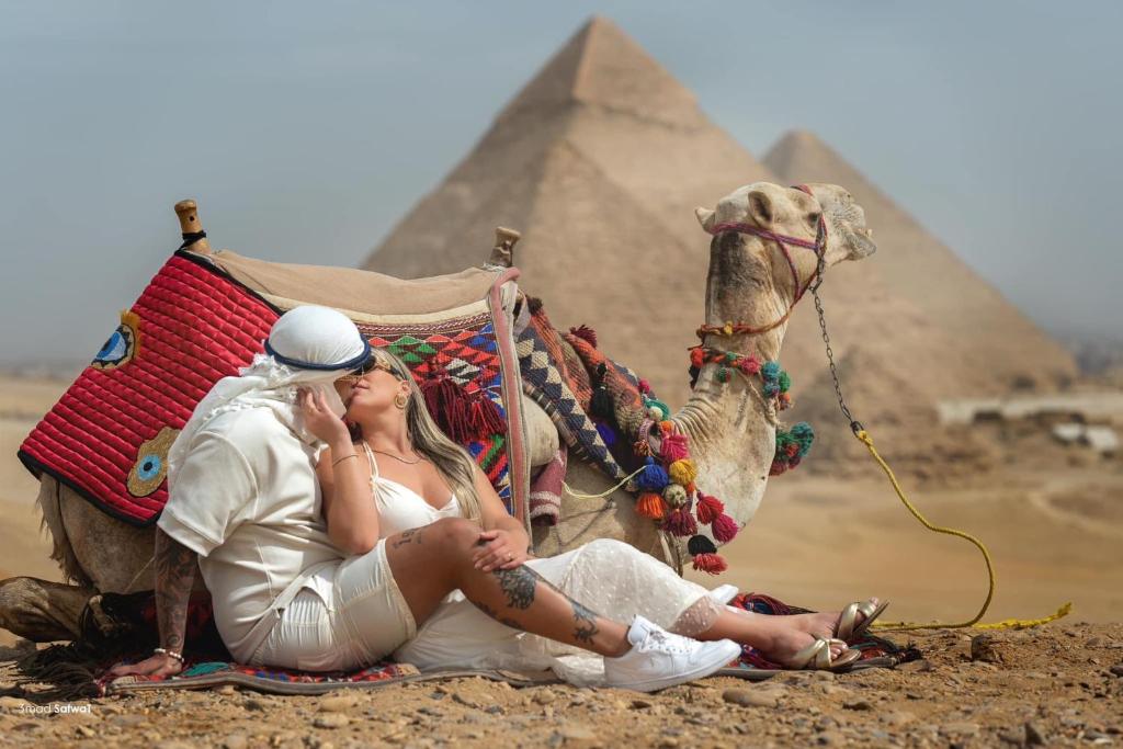 a man and woman sitting on a camel in front of the pyramids at KORAYA sunshine INN in Cairo