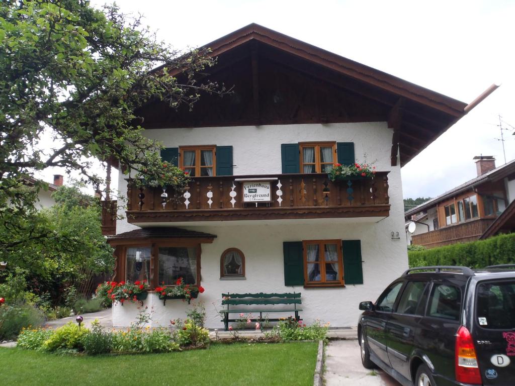 ein weißes Haus mit einem Balkon und einem Auto vor dem Haus in der Unterkunft Ferienhaus Bergfreund in Mittenwald