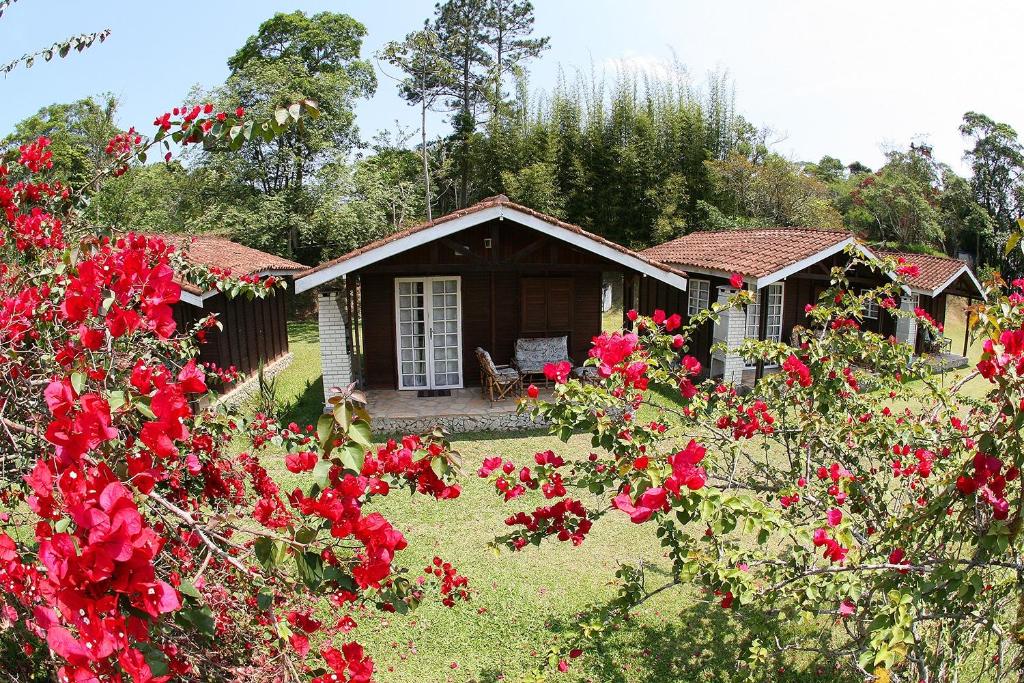 a small cabin with red flowers in front of it at Chalé Hibisco Amarelo in Juquitiba
