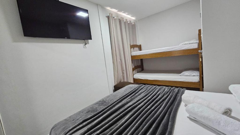 ein kleines Zimmer mit einem Bett, einem Fernseher und Etagenbetten in der Unterkunft Apto Diamante in Boa Vista