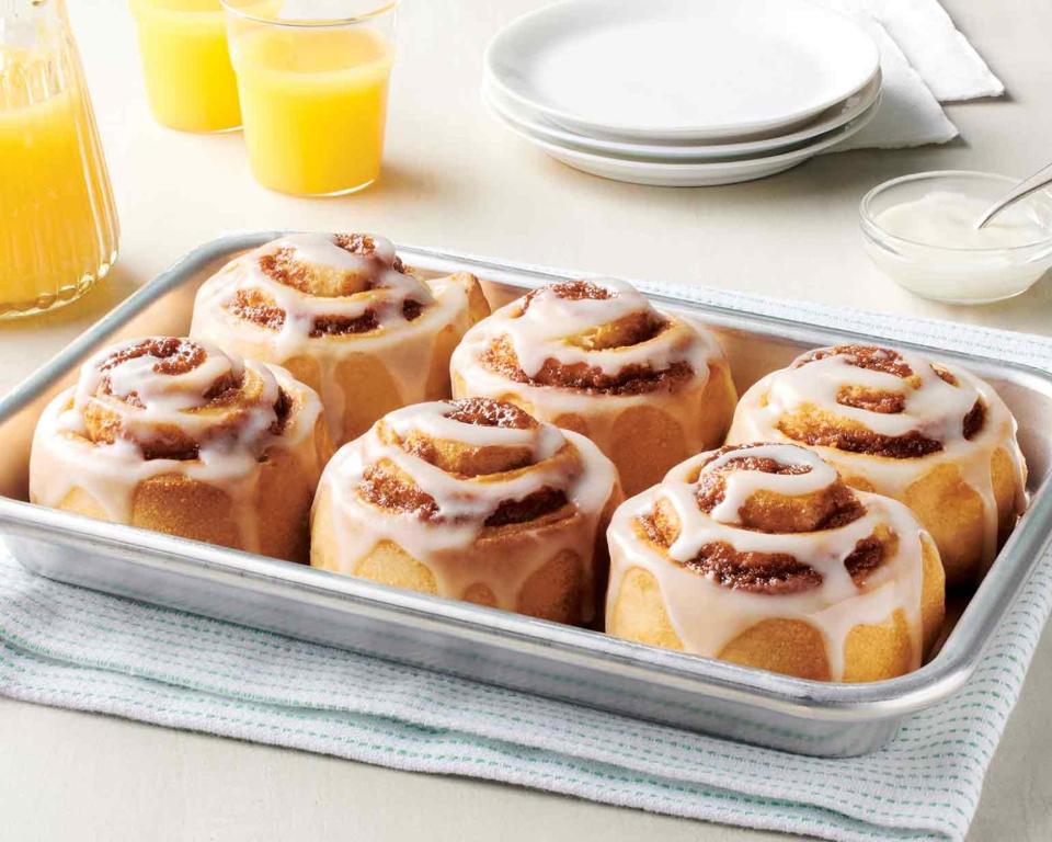 a tray of cinnamon rolls with icing on a table at Chaparral Motor Inn in Burlington