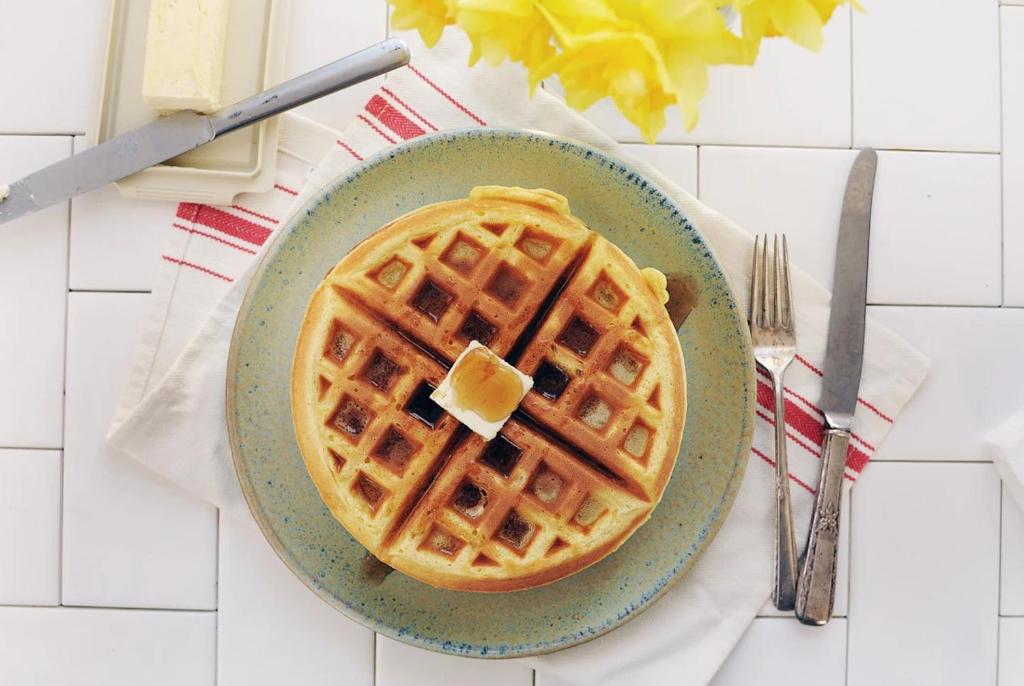 a plate of waffles with a piece of butter on it at Chaparral Motor Inn in Burlington
