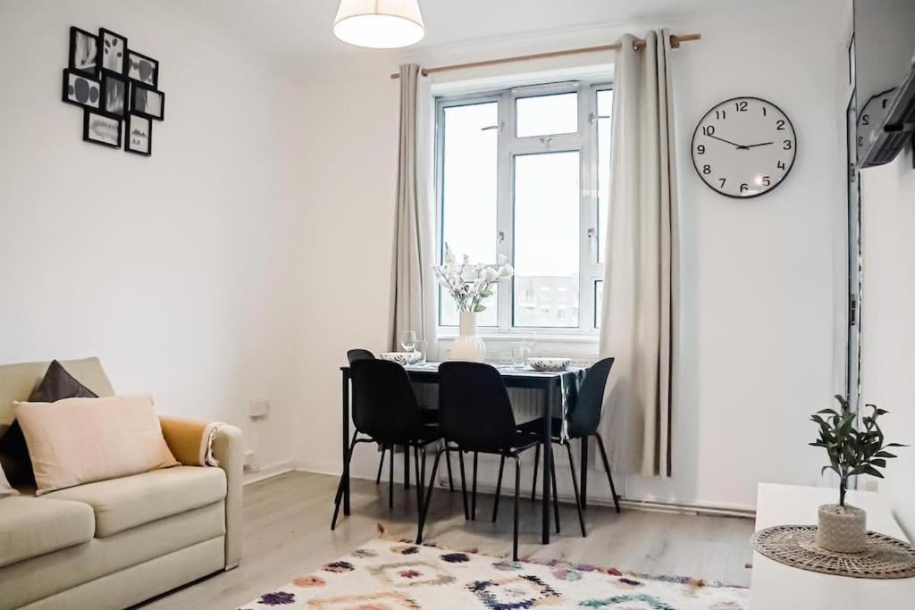 Una sala de estar con una mesa y un reloj en la pared. en Spacious 3 Bedroom Flat, en Londres