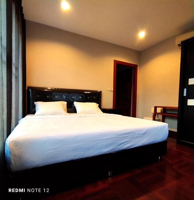 a bedroom with a large bed with white sheets at CHILLI's Homes2 in Chiang Mai