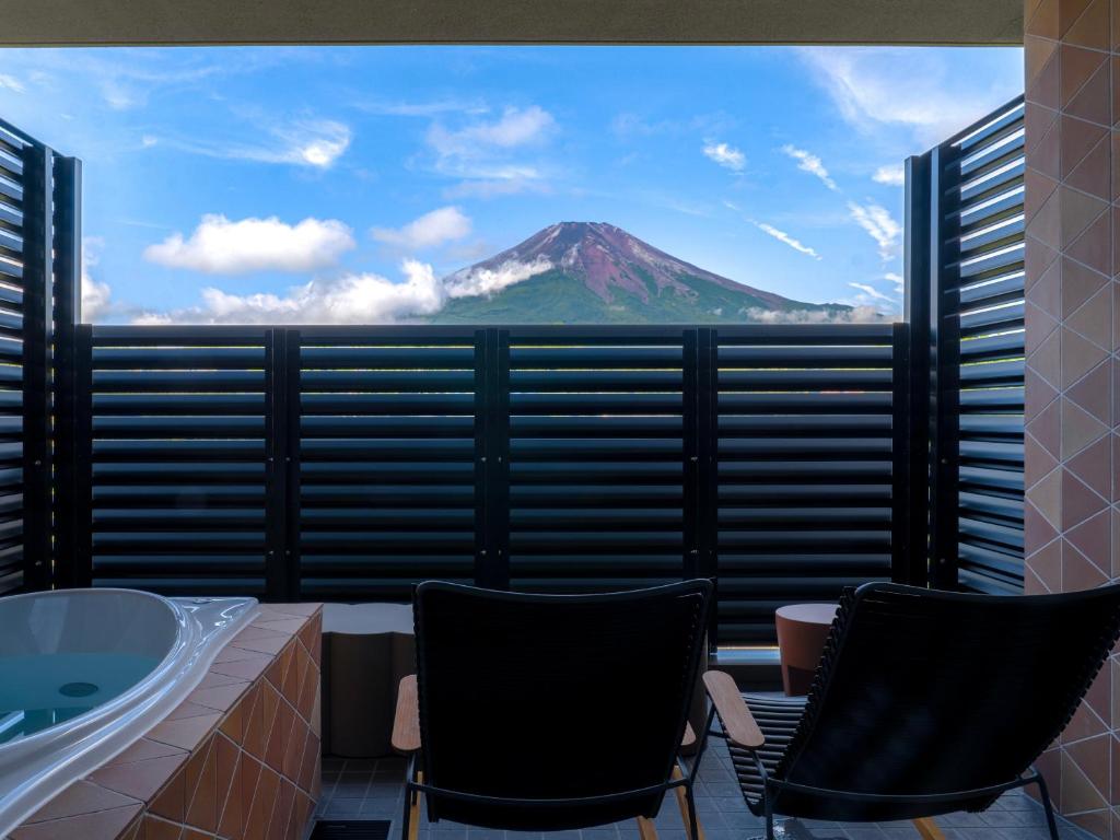 a bathroom with two chairs and a view of a mountain at Mt Fuji View and Private Sauna Ryokan Shizuku in Yamanakako