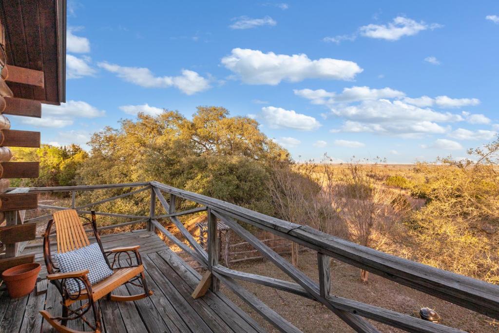 a deck with two chairs and a view of a field at Mighty Oak Log Cabin in Fredericksburg