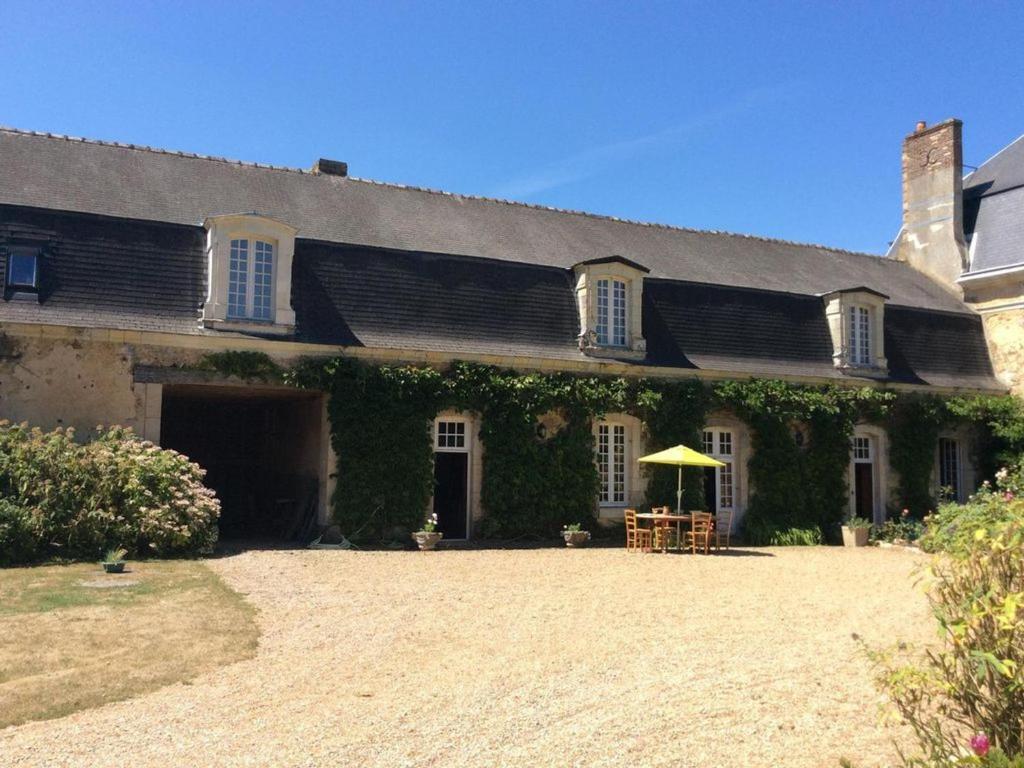 a house with an ivy covered building with a patio at Gîte historique au château de charme proche du Mans - FR-1-410-453 in Saint Pavace