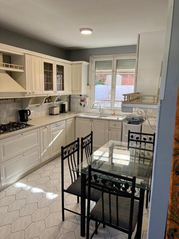 une cuisine avec des placards blancs et une table et des chaises en verre dans l'établissement Maison, Proxi Proximité campus, INSA doua centre Villeurbanne, à Villeurbanne