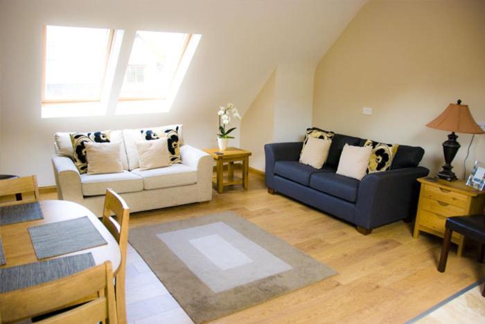 a living room with two couches and a table at Courtyard Loft in Armagh