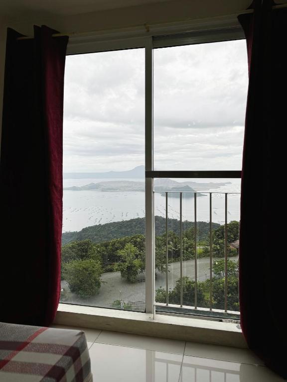 a bedroom window with a view of the ocean at Wind Suites Tagaytay at SMDC in Tagaytay