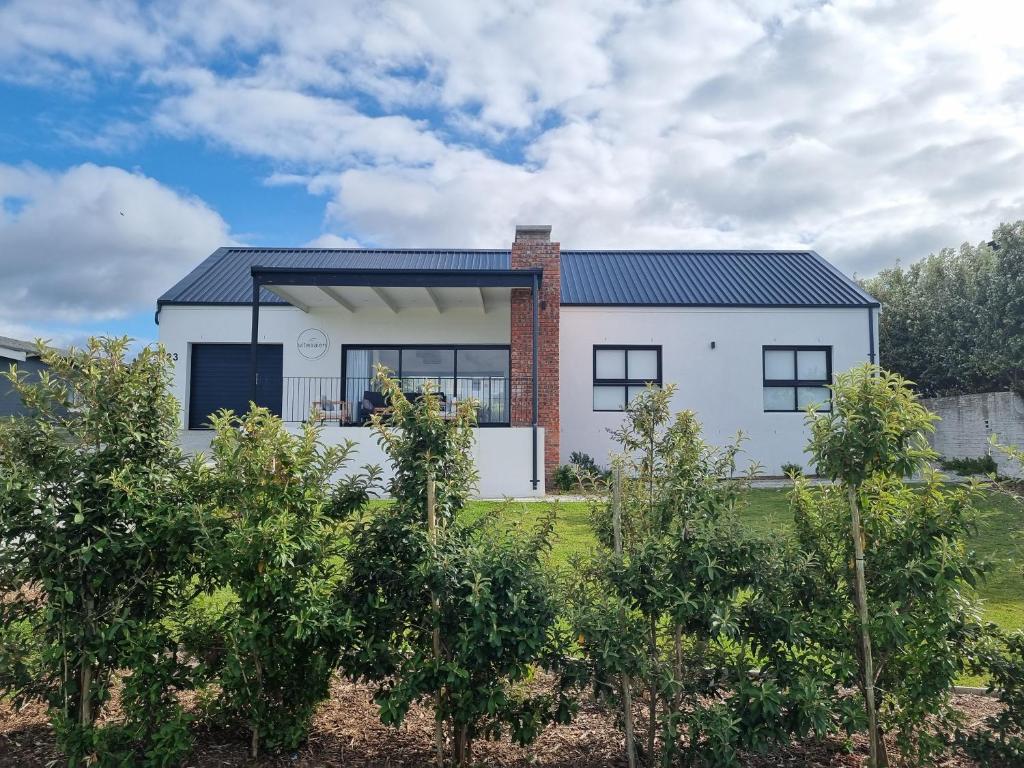a white house with a black roof at Uitwaaien Beach Cottage in Pearly Beach
