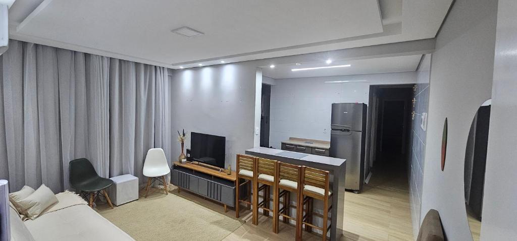 a room with a bed and a television and a kitchen at Vila Caiçara Apê a 40m da Praia in Solemar