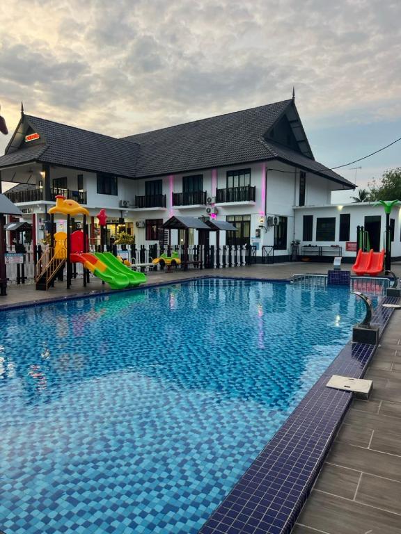 a large swimming pool with a playground in front of a building at VILLA WANIE INN in Setiu