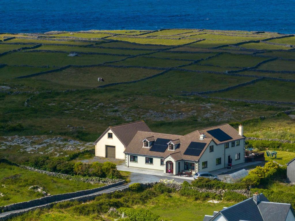 a house on a hill with the ocean in the background at Port Aran House in Kilronan